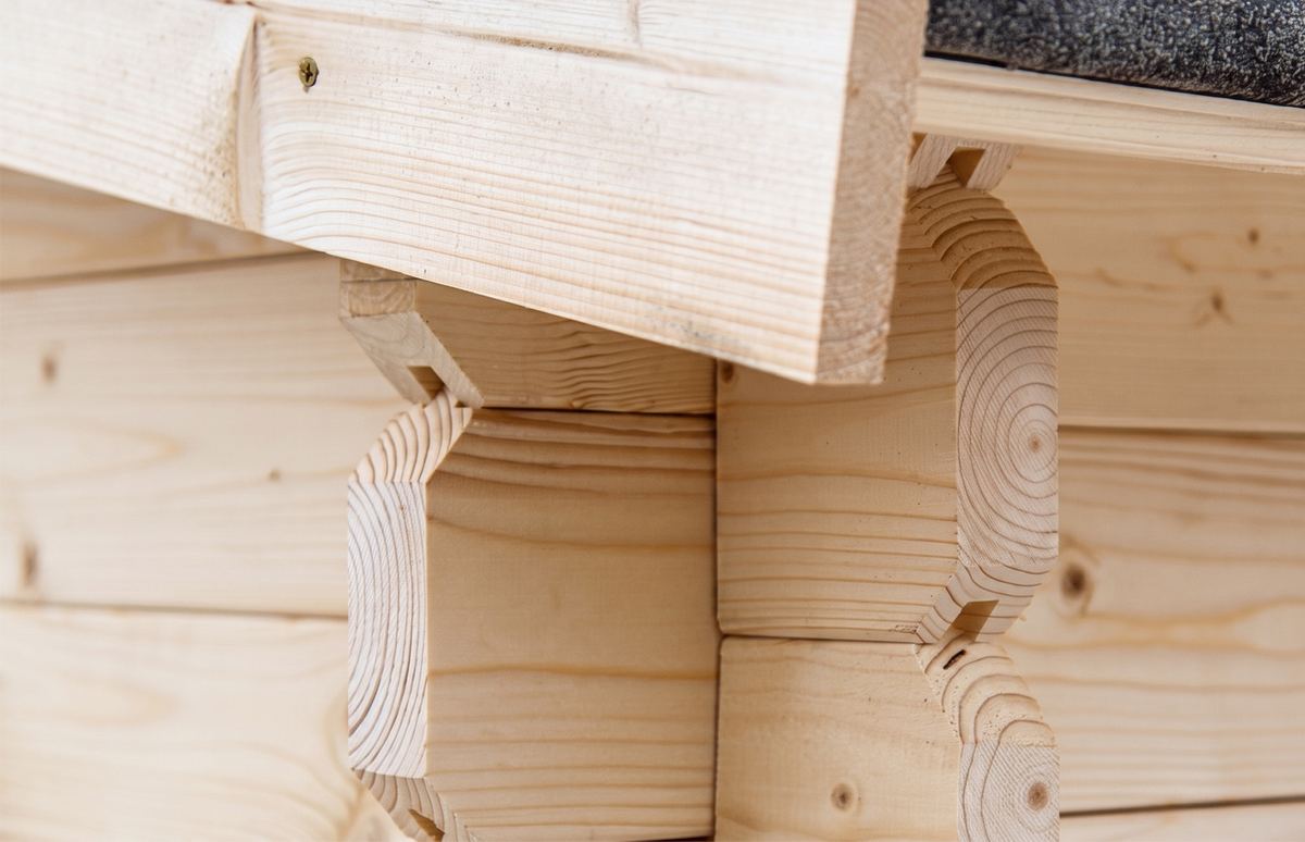 Detail: Dachüberstand und verzahnte Ecke eines Blockbohlenhauses